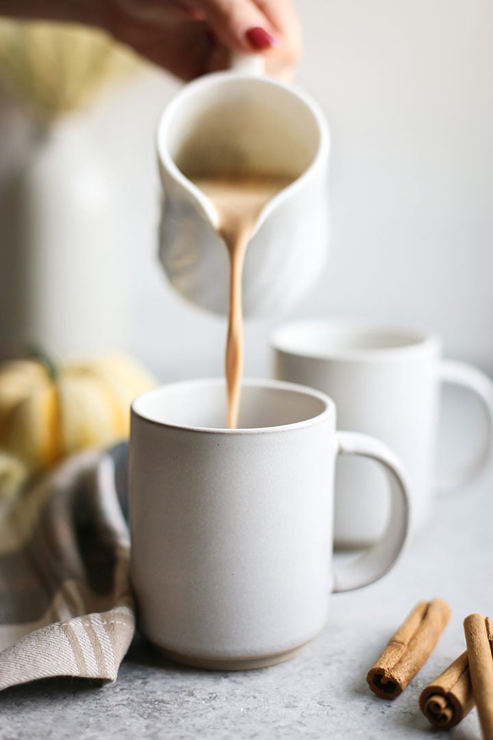 woman pouring pumpkin white hot chocolate into a mug