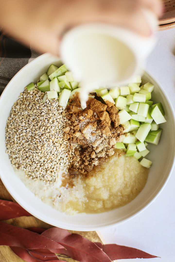 photo of a woman adding milk to a recipe for apple overnight oats