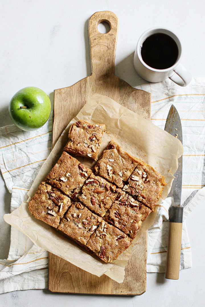 overhead photo of baked apple squares on a cutting board being cut