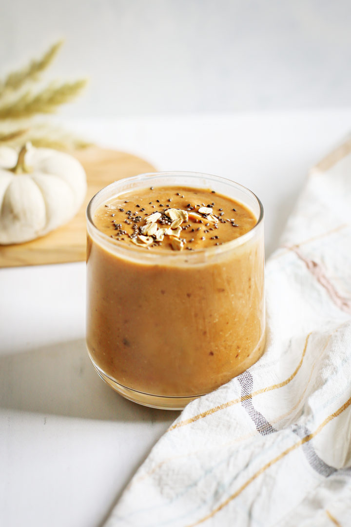 pumpkin smoothie in a glass next to a white pumpkin