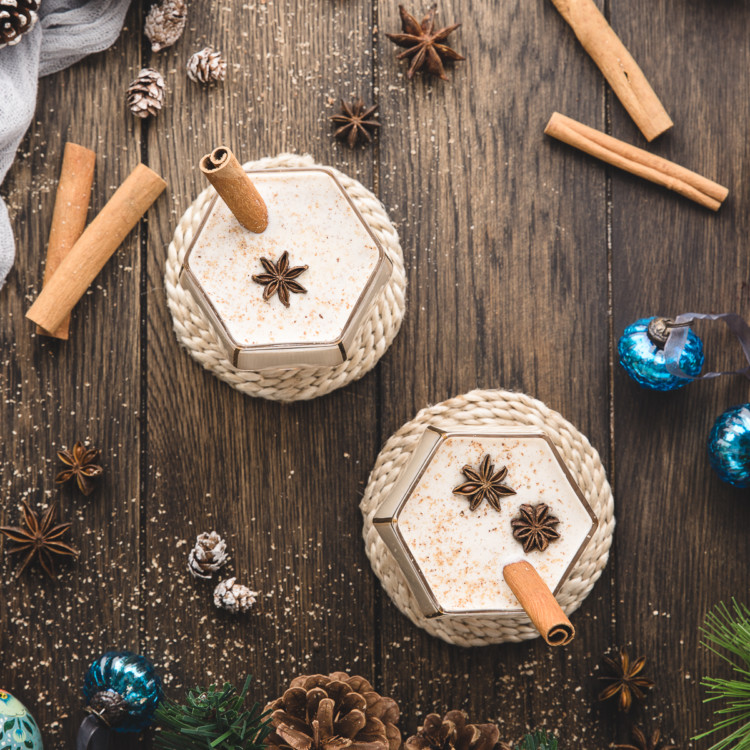 overhead photo of two glasses of spiked eggnog on a wooden table