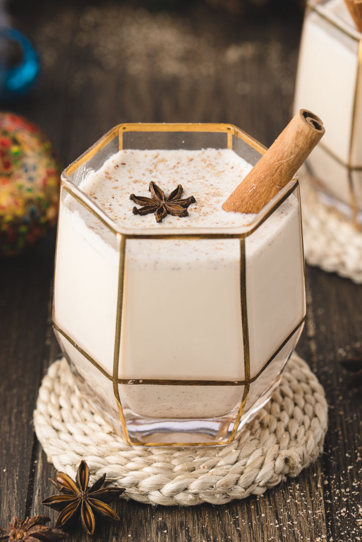 photo of a class of homemade spiked eggnog on a table with christmas ornaments