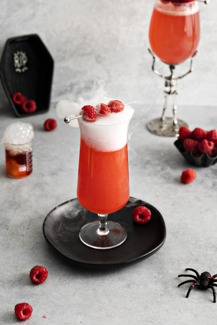 photo of a halloween gin cocktail with dry ice and raspberries