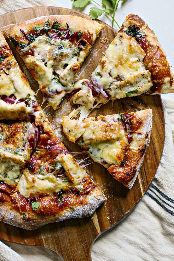 overhead photo of a bbq chicken pizza sliced on a wooden pizza peel 