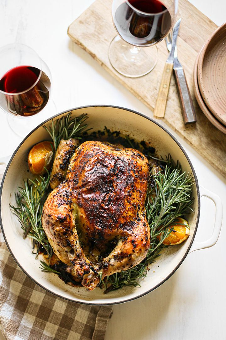 photo of rosemary roasted chicken in a white cast iron roasting pan ready to be served for an easy dinner