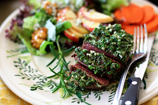 photo of sliced steak on a plate topped with mixed herb gremolata