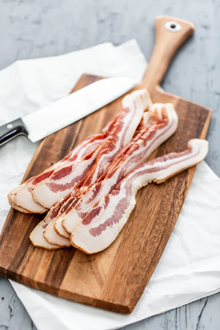 photo of bacon on a wooden cutting board for use in a roasted brussel sprouts with bacon recipe