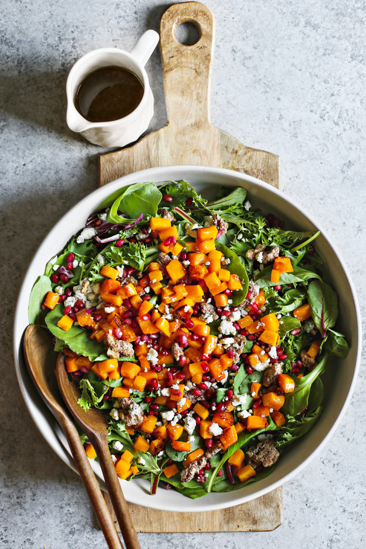 overhead photo of a salad bowl of roasted squash salad on a wooden cutting board 