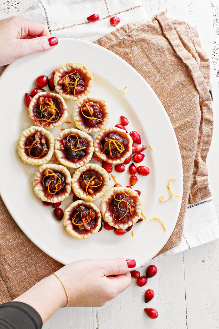 photo of a woman serving a platter of cranberry tarlets