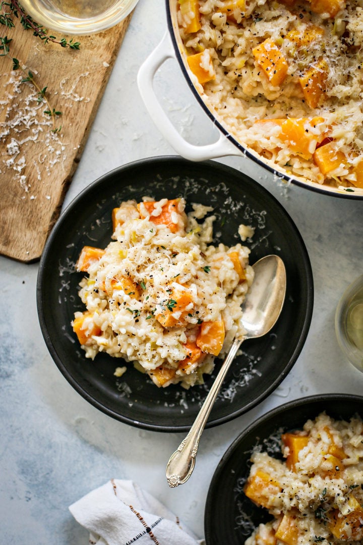 butternut squash risotto on 2 black plates set on a table 