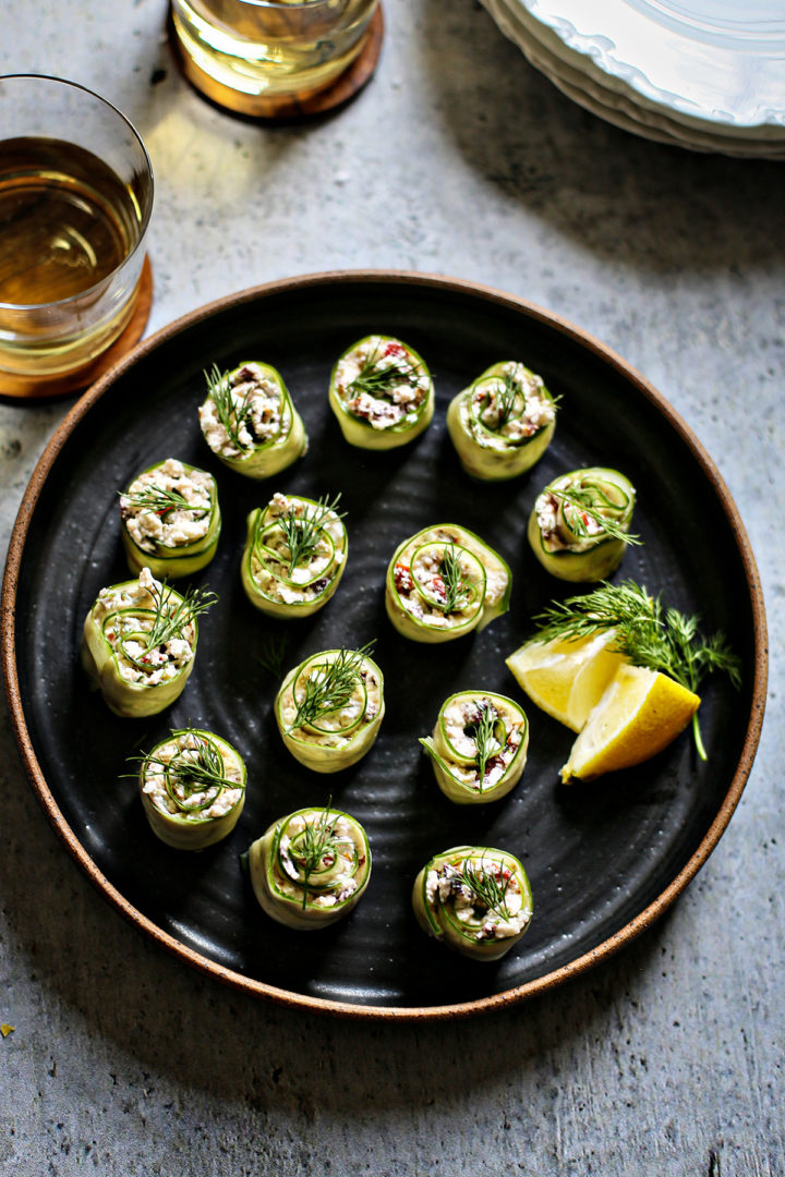 Easy Cucumber Appetizer on a black plate with glasses of wine