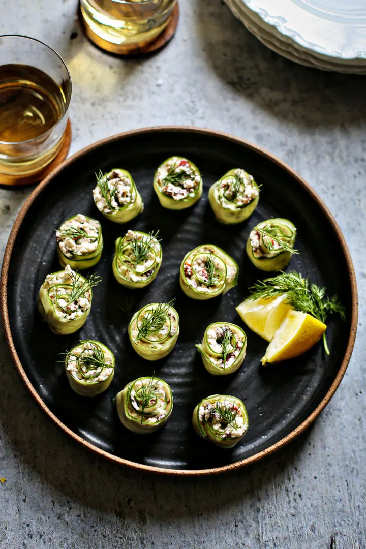 cucumberfetarolls Easy Cucumber Appetizer on a black plate with glasses of wine