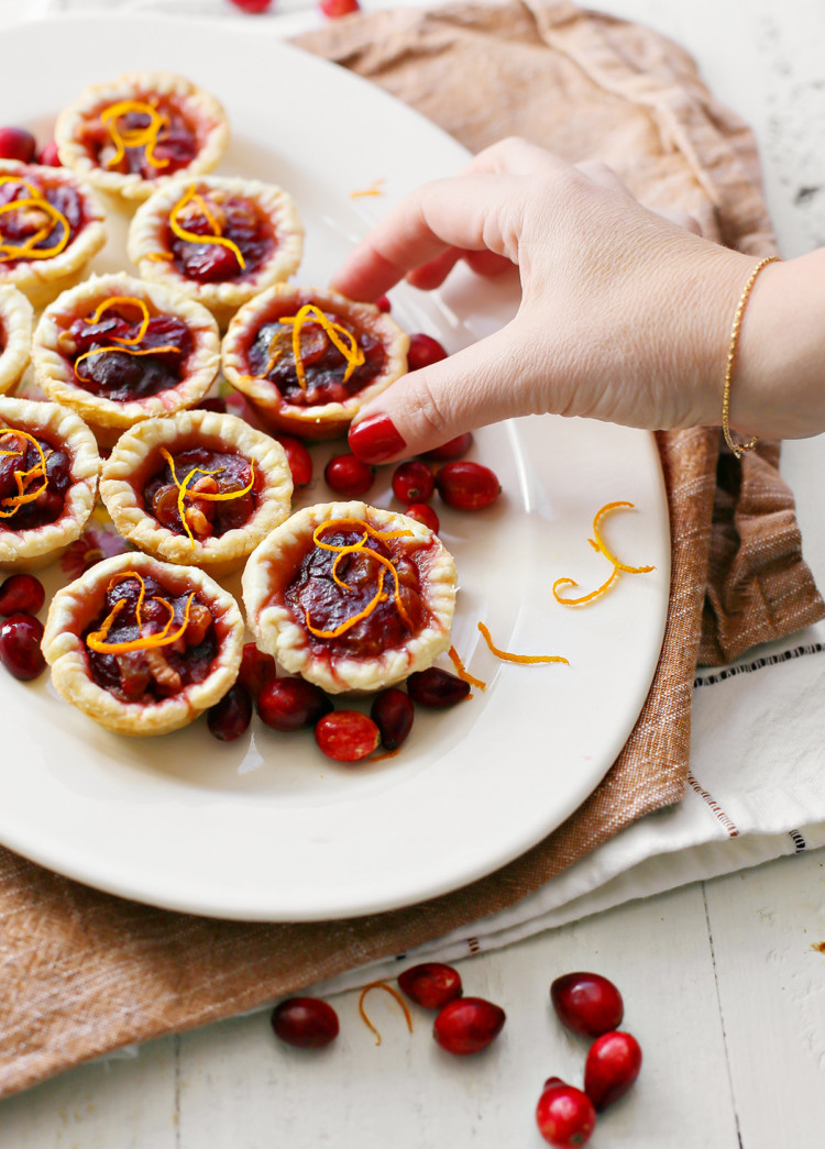woman picking up a cranberry tart of a plate