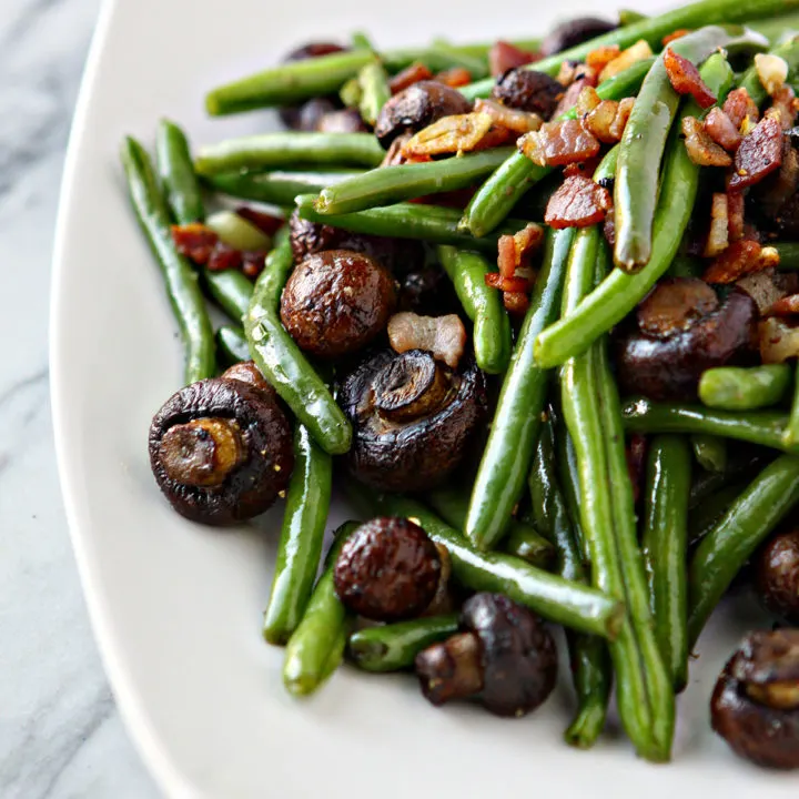 photo of Sautéed Green Beans with bacon and mushrooms on a white serving plate for thanksgiving
