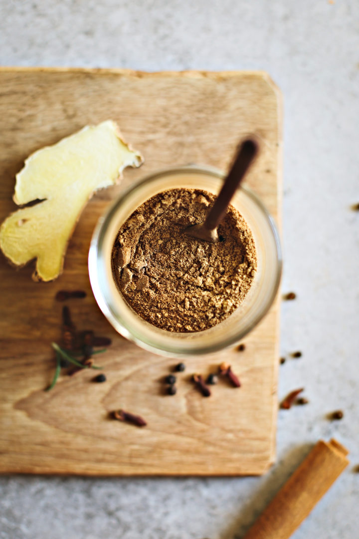 photo of homemade gingerbread spice mix in a jar on a cutting board with a spoon