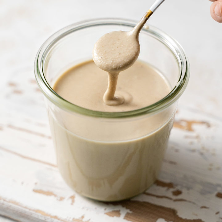 photo of a jar of homemade tahini with a spoon
