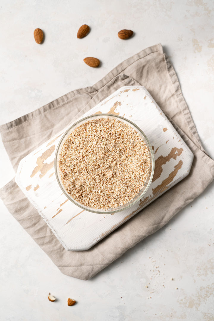 overhead photo of a bowl of homemade almond meal on a kitchen counter