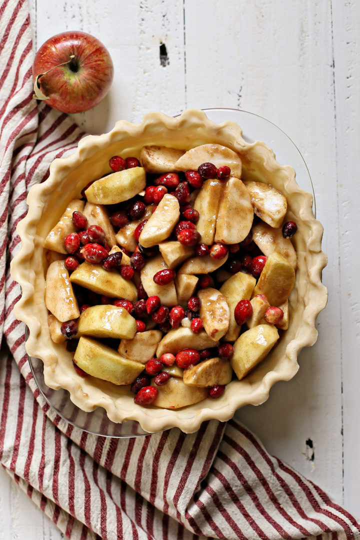 overhead photo of apples and cranberries in a pie crust before baking an apple cranberry pie