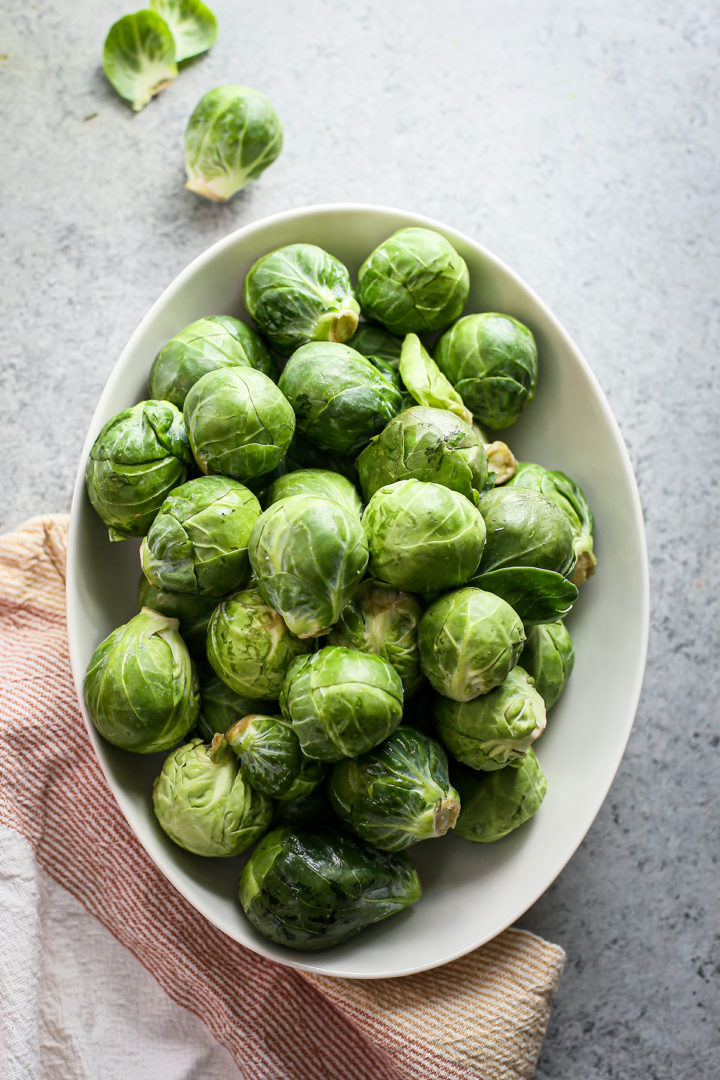 photo of brussels sprouts in a white bowl for use in a roasted brussel sprout recipe