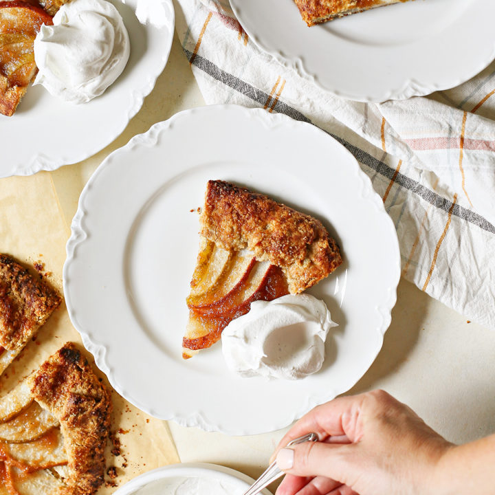 photo of a woman putting whipped cream on plates of pear galette