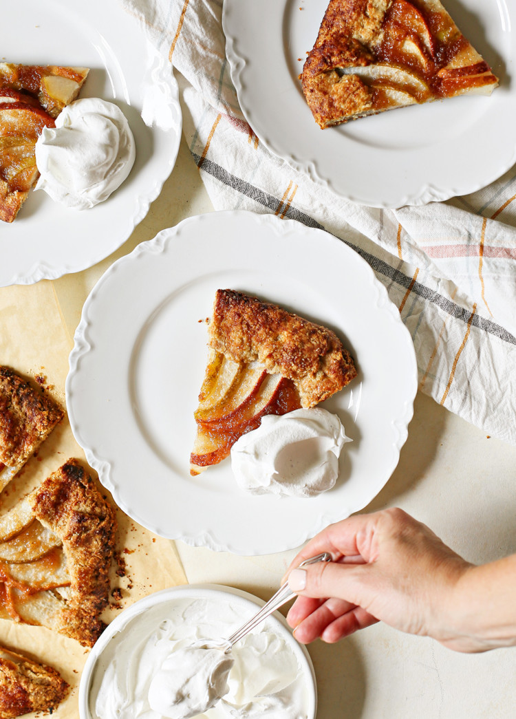 photo of a woman putting whipped cream on plates of pear galette