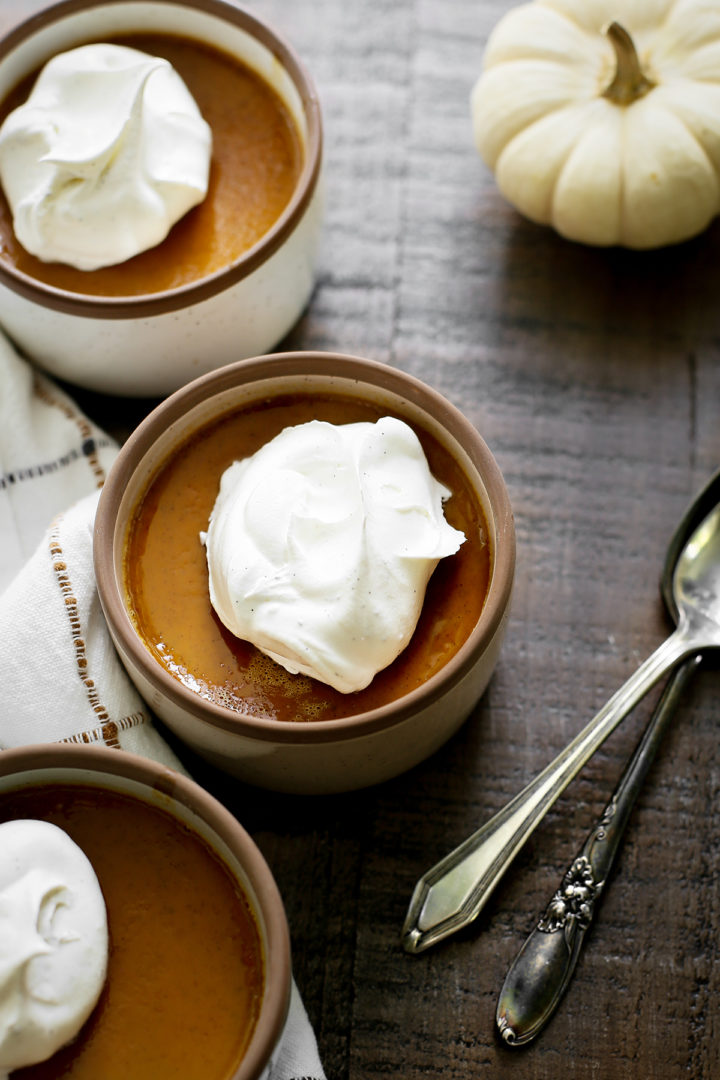 photo of three cups of pumpkin custard on a wooden table with spoons