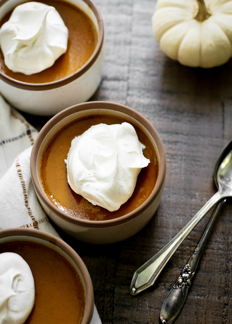 photo of three bowls of pumpkin custard on a wooden table with spoons