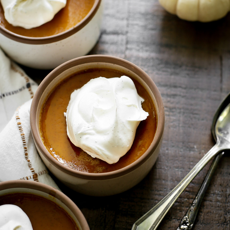 photo of three bowls of pumpkin custard on a wooden table with spoons