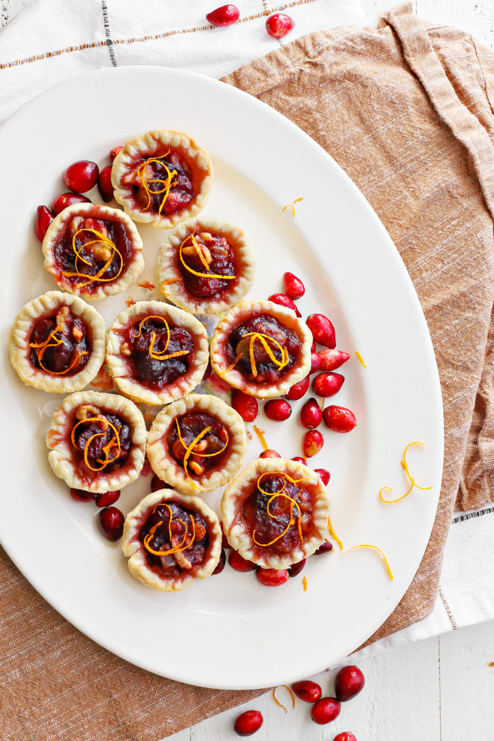 photo of a white platter with cranberry tartlets and fresh cranberries on it