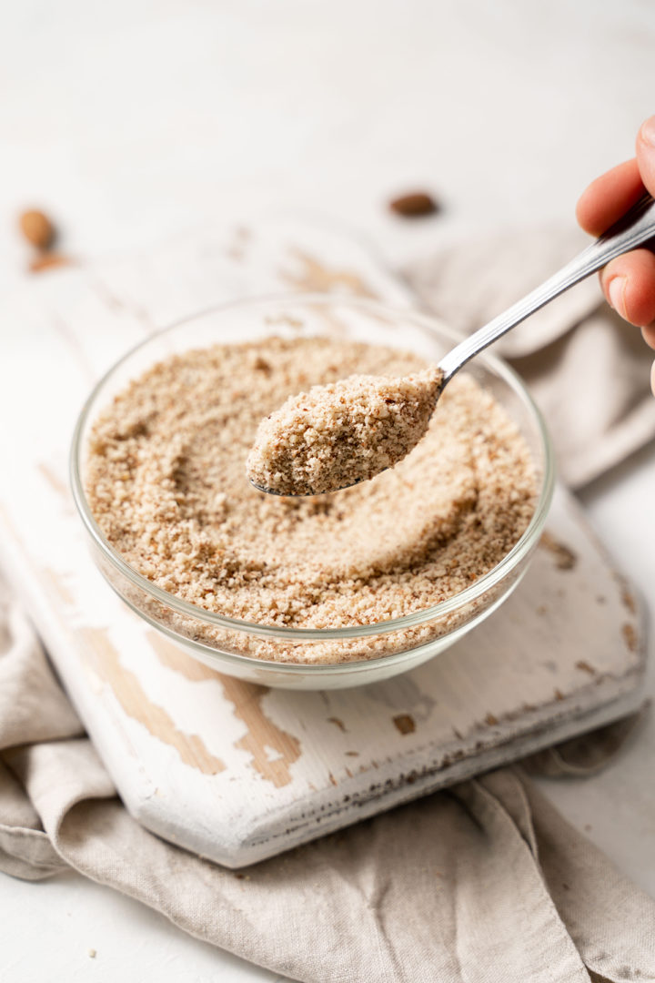 photo of a woman scooping a spoonful of almond meal out of a bowl