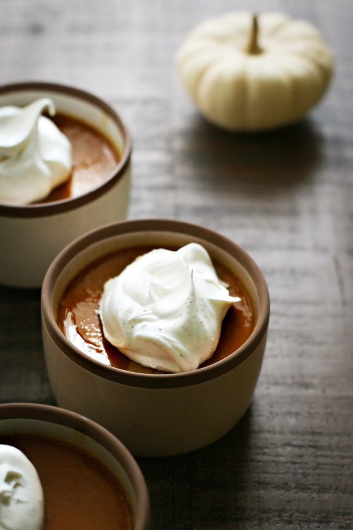 close up of a bowl of pumpkin custard with vanilla whipped cream on top