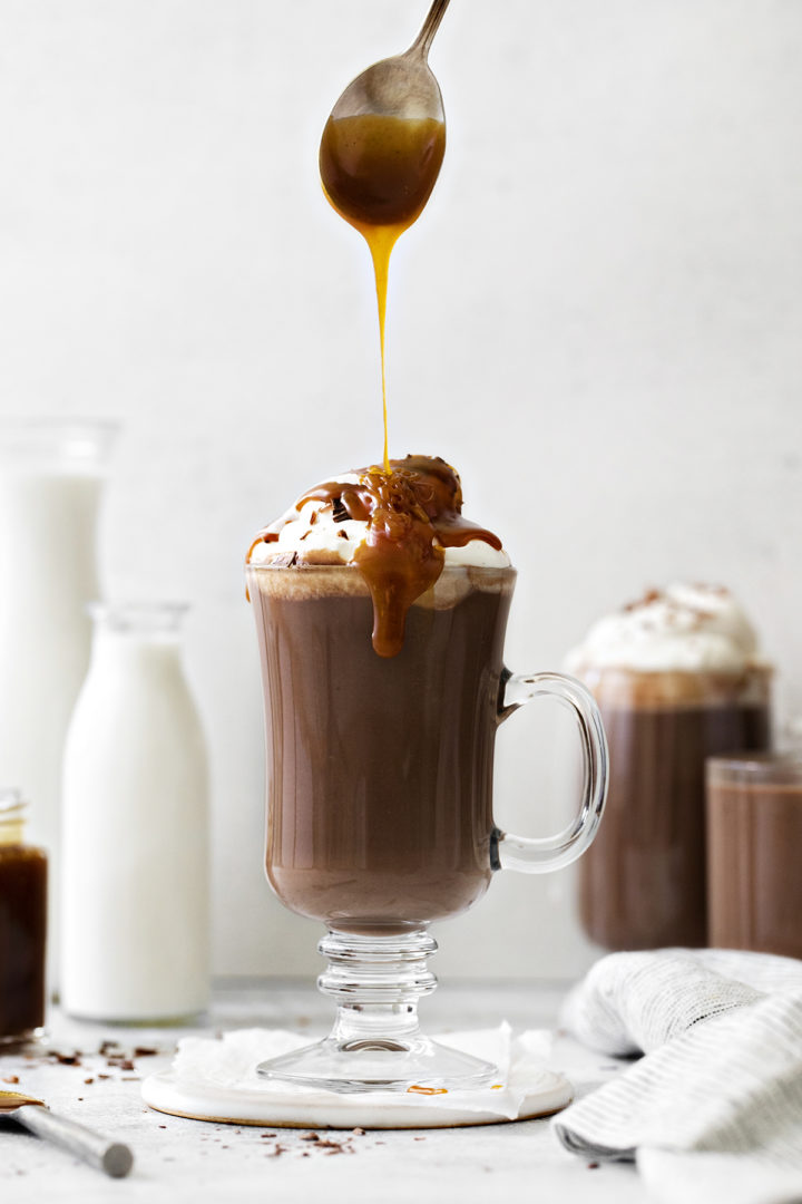 photo of salted caramel being spooned into a mug of salted caramel hot chocolate