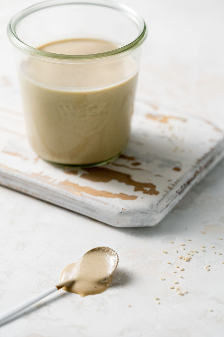 a jar of homemade tahini on a wooden cutting board