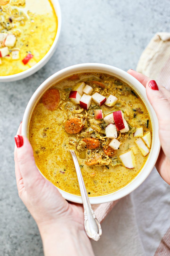 woman holding a bowl of turkey curry with a spoon