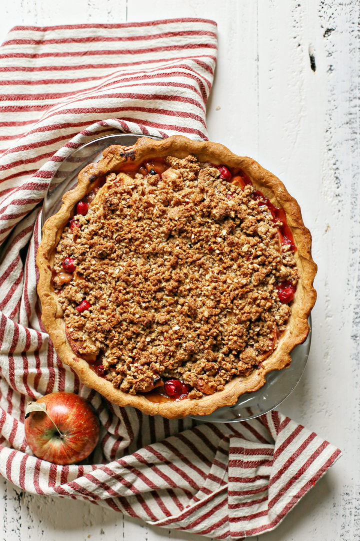 overhead photo of a deep dish cranberry apple pie on a white wooden table