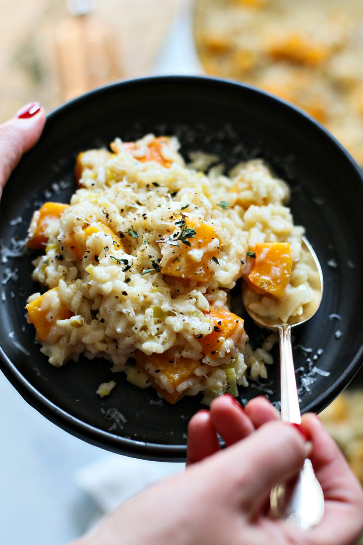 woman holding a plate of butternut squash risotto
