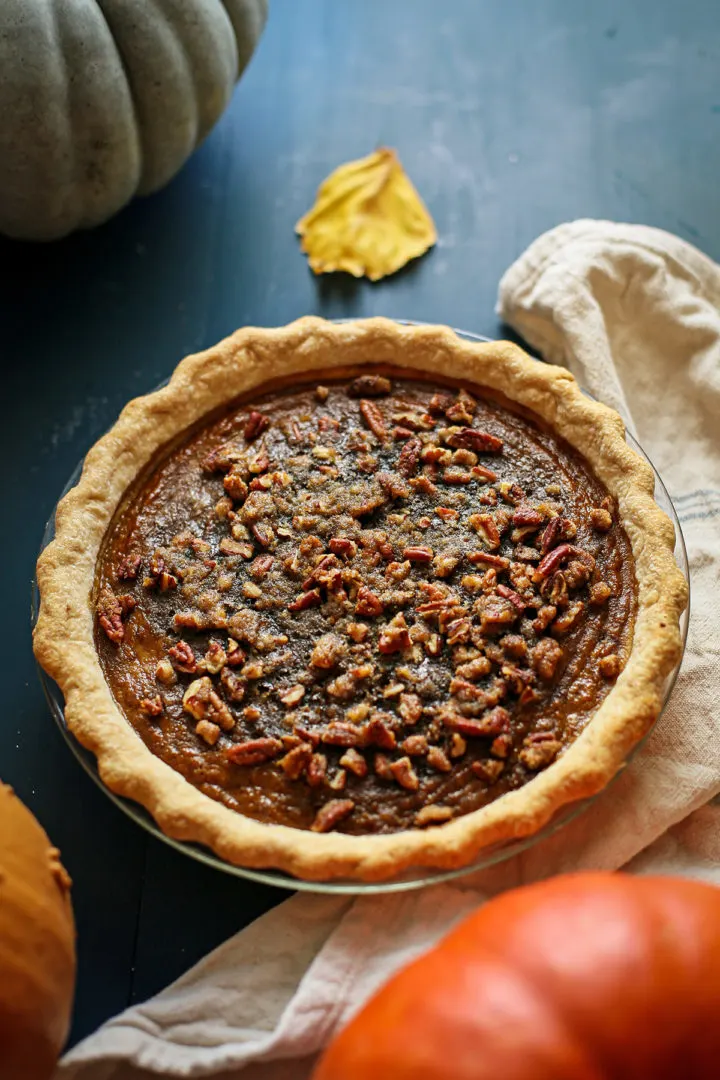 photo of an unsliced pumpkin pie with pecan topping after baking