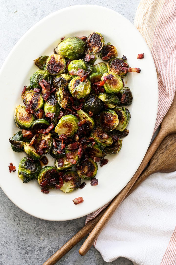 overhead photo of a white serving plate with roasted brussel sprouts and bacon