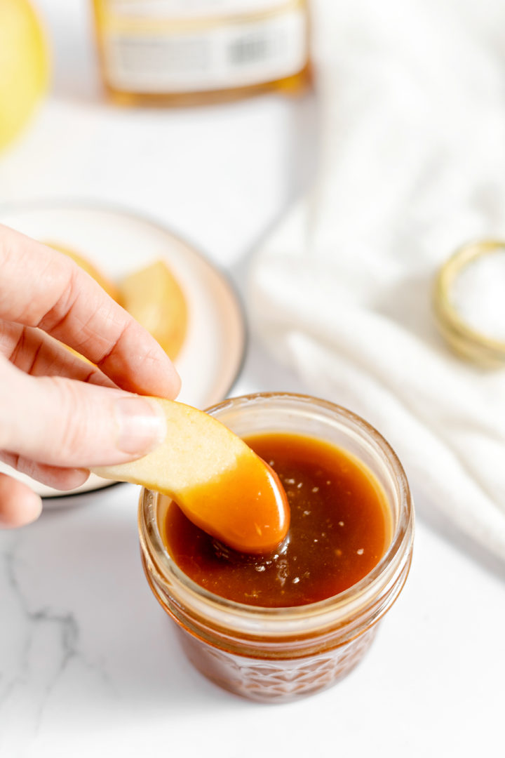 photo of a woman dipping apple slices into rum caramel sauce 