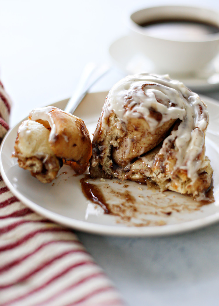 photo of a gooey cinnamon roll with bourbon cream cheese frosting on a white plate