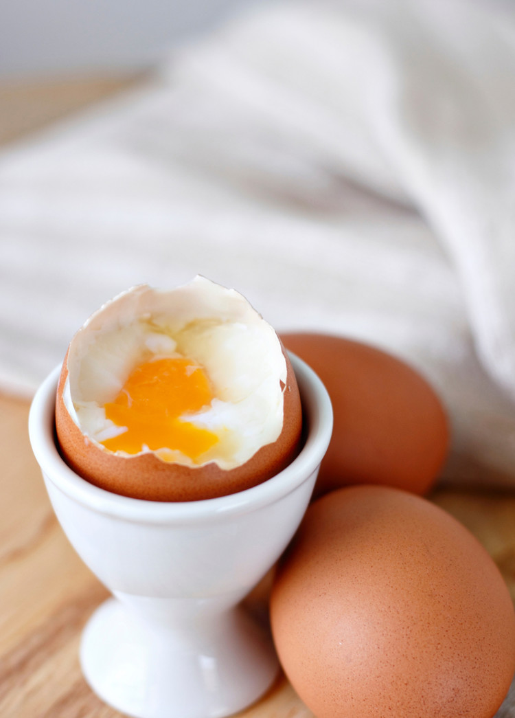 photo of a microwaved hard boiled egg that has been cooked with a soft yolk being served in a white egg cup