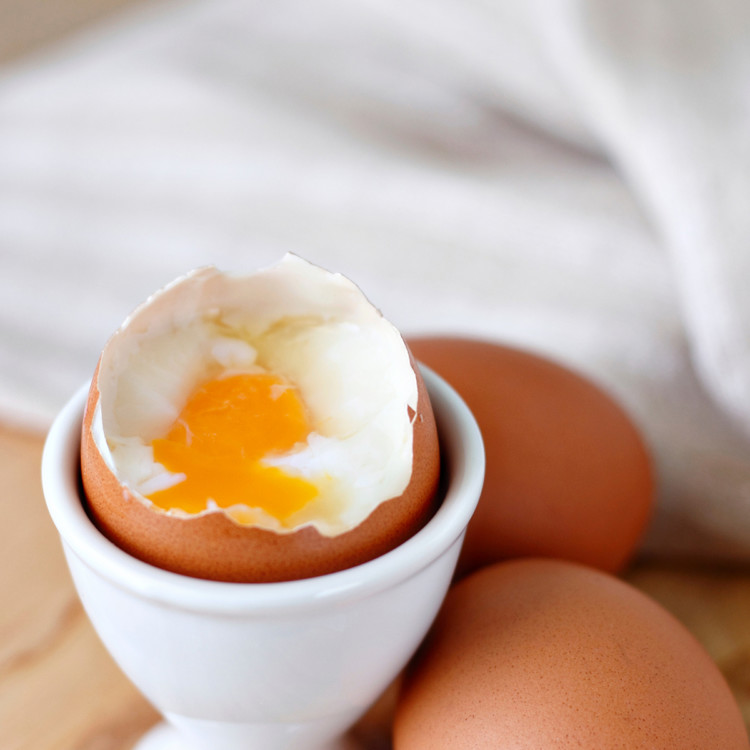 photo of a microwaved hard boiled egg that has been cooked with a soft yolk being served in a white egg cup