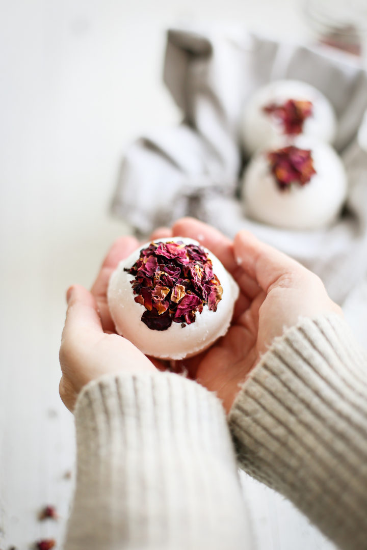 woman holding a diy bath bomb before putting it in a bath tub to show how to use a bath bomb