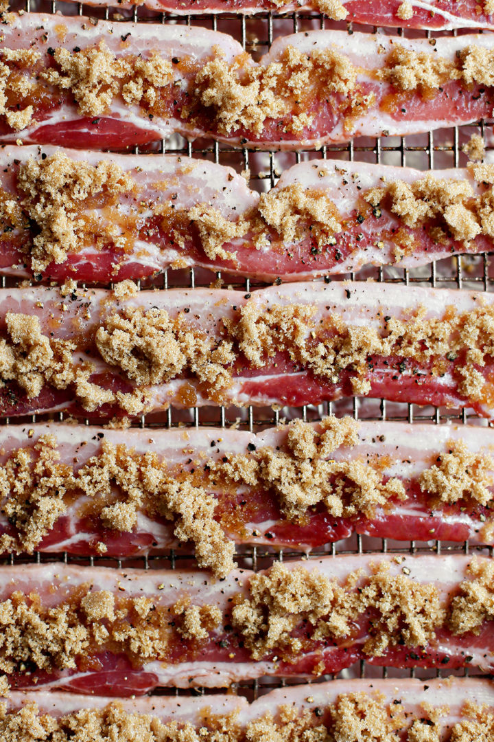 close up photo of bacon candy before baking (bacon with black pepper and brown sugar on a baking sheet)