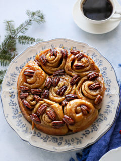 photo of pecan rolls on a plate set at a table next to a mug of coffee