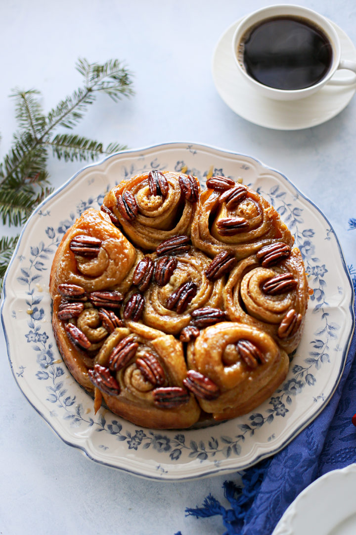 photo of a plate of pecan rolls set on a blue table next to coffee