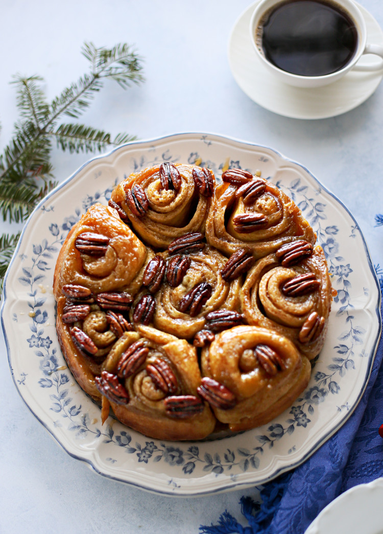 photo of pecan rolls on a plate set at a table next to a mug of coffee