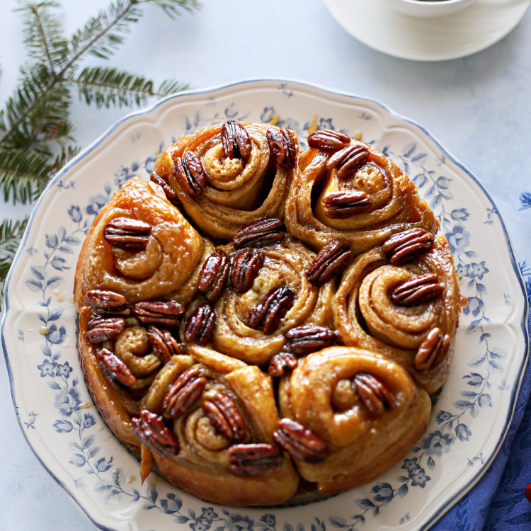 photo of pecan rolls on a plate set at a table next to a mug of coffee