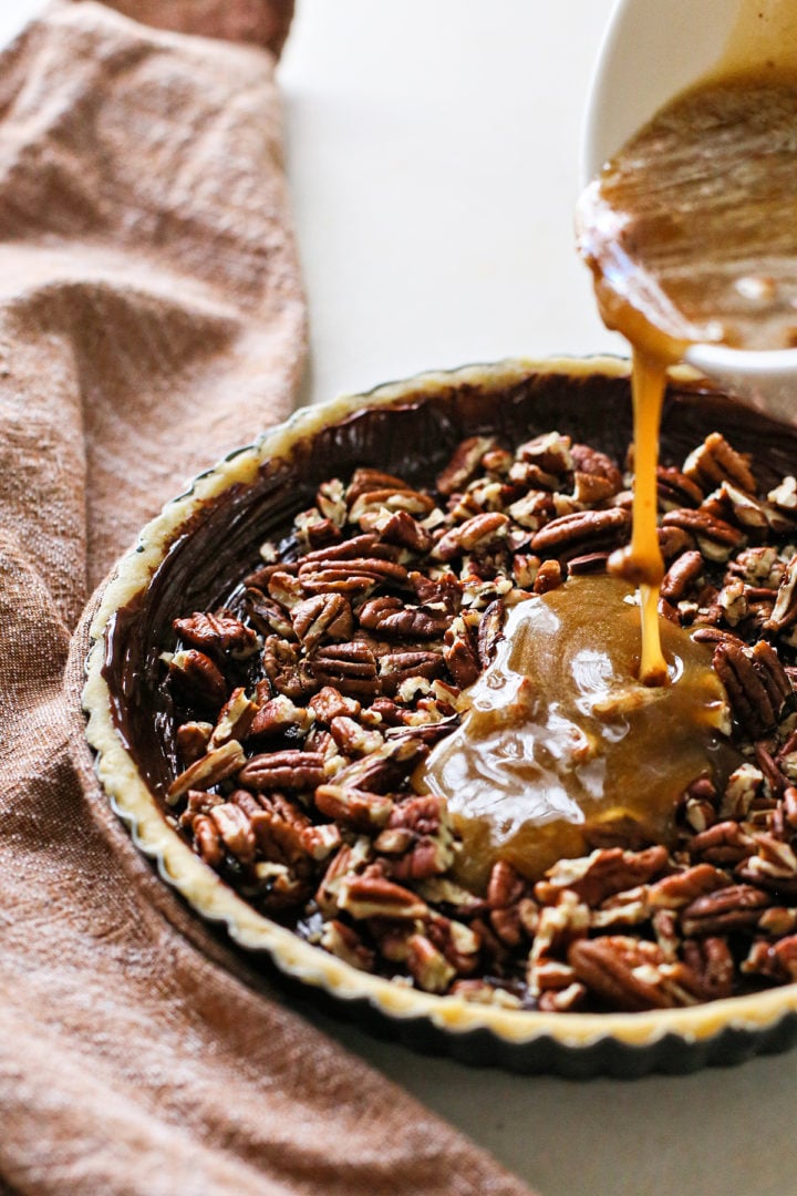 photo of the pecan filling being poured into the chocolate coated tart crust for this pecan pie tarts recipe