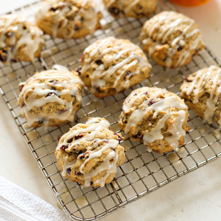 persimmon cookies drizzled with orange glaze on a wire rack with fresh persimmon in the background